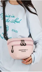 Detail of light pink nylon crossbody bag with double zippers and black strap on model