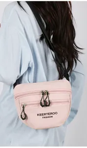 Detail of light pink nylon crossbody bag with three zipper compartments and adjustable strap