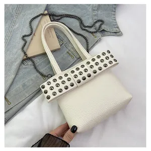 Détail de la texture cuir litchi blanc et de la sangle à rivets sur le petit sac carré