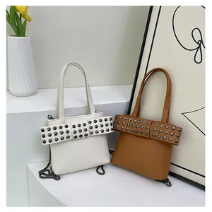 Détail de sacs à main en cuir avec de grands nœuds cloutés et des bandoulières chaînes