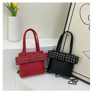 Détail de sacs en cuir grainé rouge et noir avec rivets argentés et bandoulière chaîne