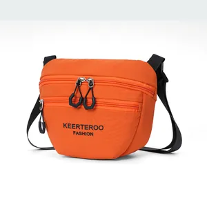 Close-up of bright orange nylon crossbody bag with double zippers and black logo strap