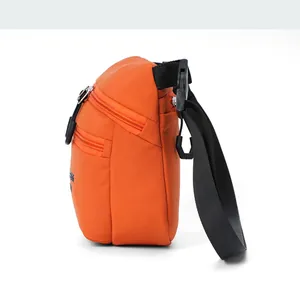 Detail view of water-resistant orange nylon crossbody bag with dual zipper pockets