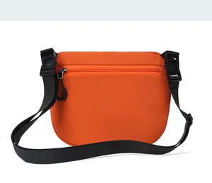 Detail view of orange nylon crossbody bag with wide black strap and plastic buckle