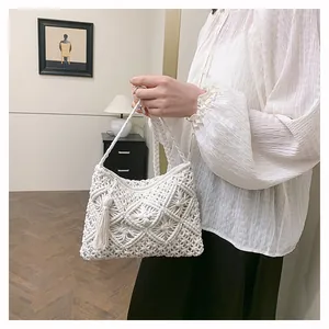 Detail of white macrame woven handbag with stylish tassels and geometric knit patterns