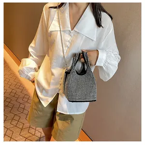 Detail of black rhinestone bucket bag with silver chain strap shown on model's shoulder