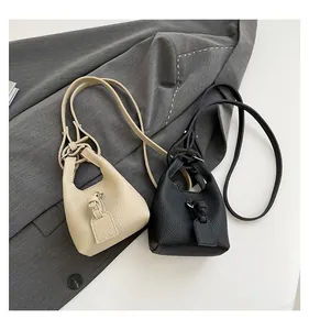 Nahaufnahme kleiner Eimertaschen aus beigem und schwarzem Leder mit Schultergurten