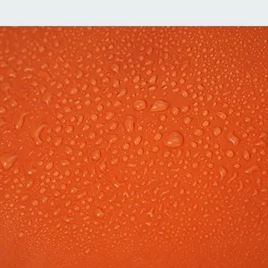 Macro detail of waterproof orange nylon fabric with water droplets on a crossbody bag