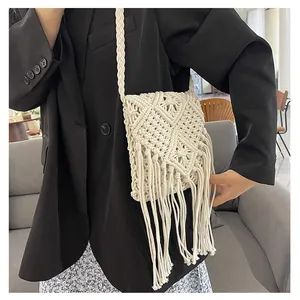 Detail of bohemian ivory macrame crossbody bag with hand-woven tassels on black blazer