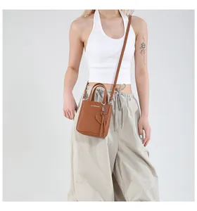 Detail of brown litchi pattern leather mini bucket bag with heart pendant and logo