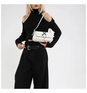 Detail of white leather shoulder bag with vintage silver cross and rivet accents