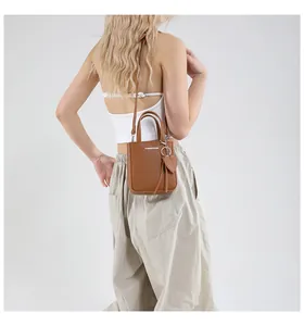 Detail of brown litchi pattern leather mini bucket bag with heart charm and strap