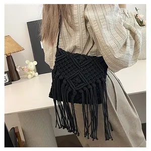 Macro view of handmade black woven shoulder bag with boho fringe and diamond patterns