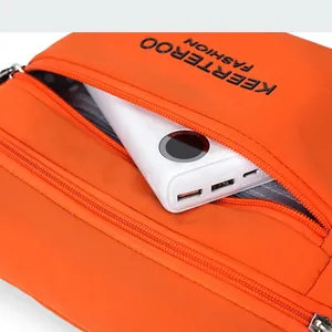 Detail view of orange nylon crossbody bag zippers and power bank storage capacity