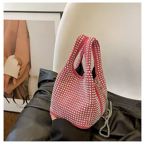 Detail shot of fuchsia rhinestone bucket bag with silver chain on black leather background