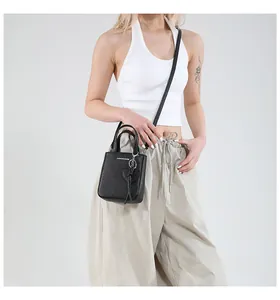 Detail of black textured leather bucket bag with heart tassel and fashion lettering