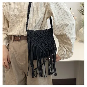 Macro detail of black handmade macrame crossbody bag with long fringes and woven strap
