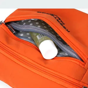 Detail of orange nylon bag with metal zipper and gray polka dot lining for storage