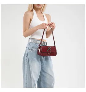 Close-up of dark red patent leather crossbody bag with silver cross and metal chain