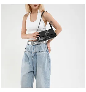 Detail of black leather punk crossbody bag with silver cross charm and rivet studs