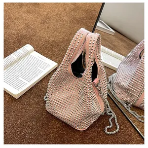 Detailed view of pink bucket bag with silver rhinestones and chain strap on a textured rug