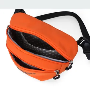 Detail of bright orange nylon crossbody bag showing zip pockets and polka dot lining