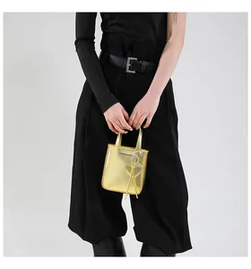Detailed macro of golden metallic mini bucket bag featuring heart charm and fashion text