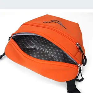 Macro view of orange nylon crossbody bag showing dual zipper pockets and polka dot lining