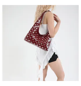 Detail of burgundy oil wax leather tote featuring silver rivets on a half-moon shoulder bag