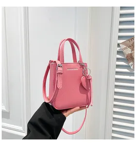 Detailed macro shot of pink lychee grain leather handbag with heart charm and silver logo