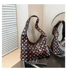 Close-up of dark brown wax leather tote with silver studs and polished mirror reflection
