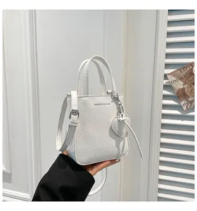 Detail of white lychee pattern bucket bag with heart charm and FASHION & BAGS text