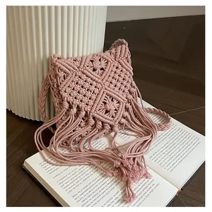 Macro detail of handmade cotton woven bag featuring tassel fringe and bohemian pink pattern
