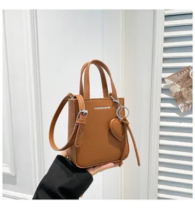 Detailed macro of brown lychee grain leather bucket bag with silver hardware and heart charm