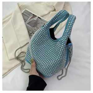 Close-up of light blue mini handbag with silver rivets and metallic chain strap