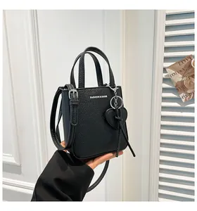 Close-up of black lychee grain mini bucket bag with fashion logo and heart pendant charm