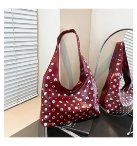 Macro detail of wine red glossy leather tote with silver rivets on a display setup