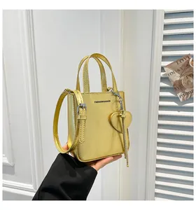 Detailed macro view of the golden bucket bag with heart pendant and fringe detail