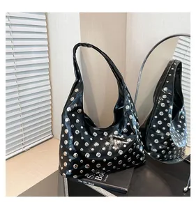 Detail of black oiled leather tote bag featuring shiny silver rivets and crescent shape
