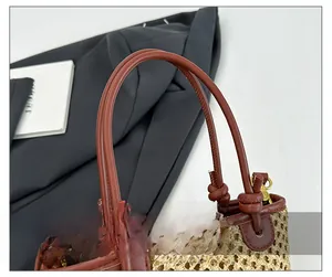 Detail of woven straw bucket bag showing PU leather handle and bronze metal hardware