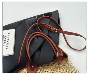 Detail showing adjustable leather strap and woven raffia texture of the bucket bag