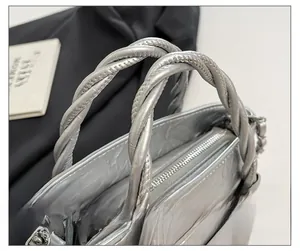 Close-up of metallic silver bucket bag featuring twisted handles and top zipper detail