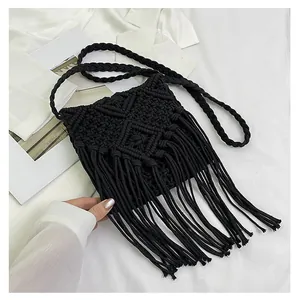 Close-up of black handmade crochet crossbody bag with long fringes and woven strap