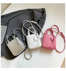 Close-up of mini bucket bags in silver, white, and pink with heart charms and straps