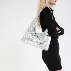 Silver punk hobo bag with metal rivets and glossy finish on a fashion model