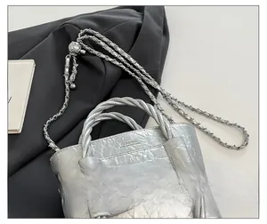 Detail of silver pleated leather bag with woven handle and classic embossed logo
