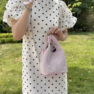 Pink rhinestone bucket bag with silver chain strap shown in an outdoor fashion setting
