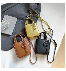 Detailed trio of mini tote bags in gold, brown, and black with heart charms and straps