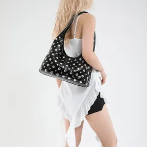 Black punk style studded tote bag made of oil wax leather worn by a female model