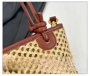 Close-up of woven bucket bag with brown leather strap and gold-tone metal hardware